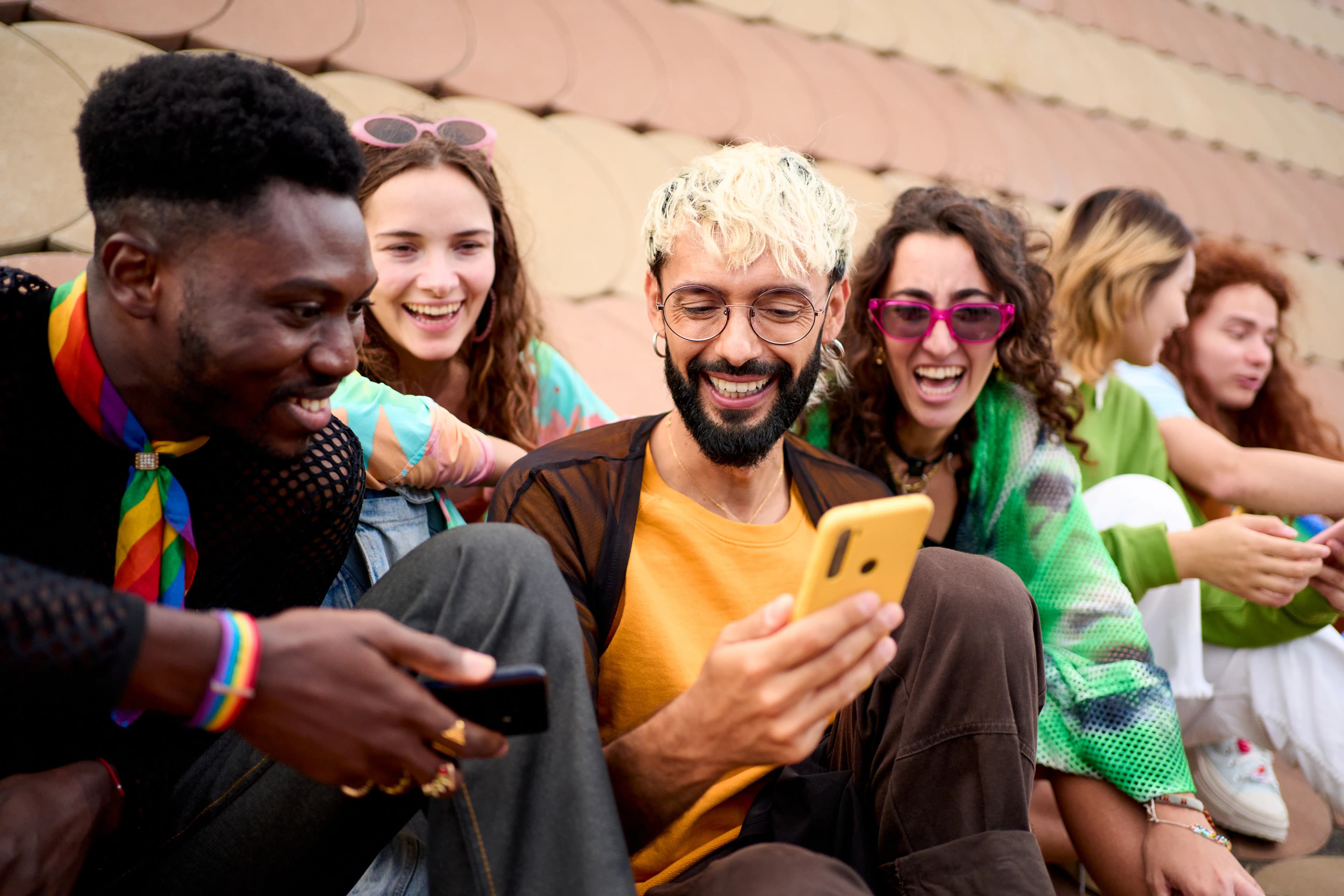 A group of friends laughing together as they look at a smartphone