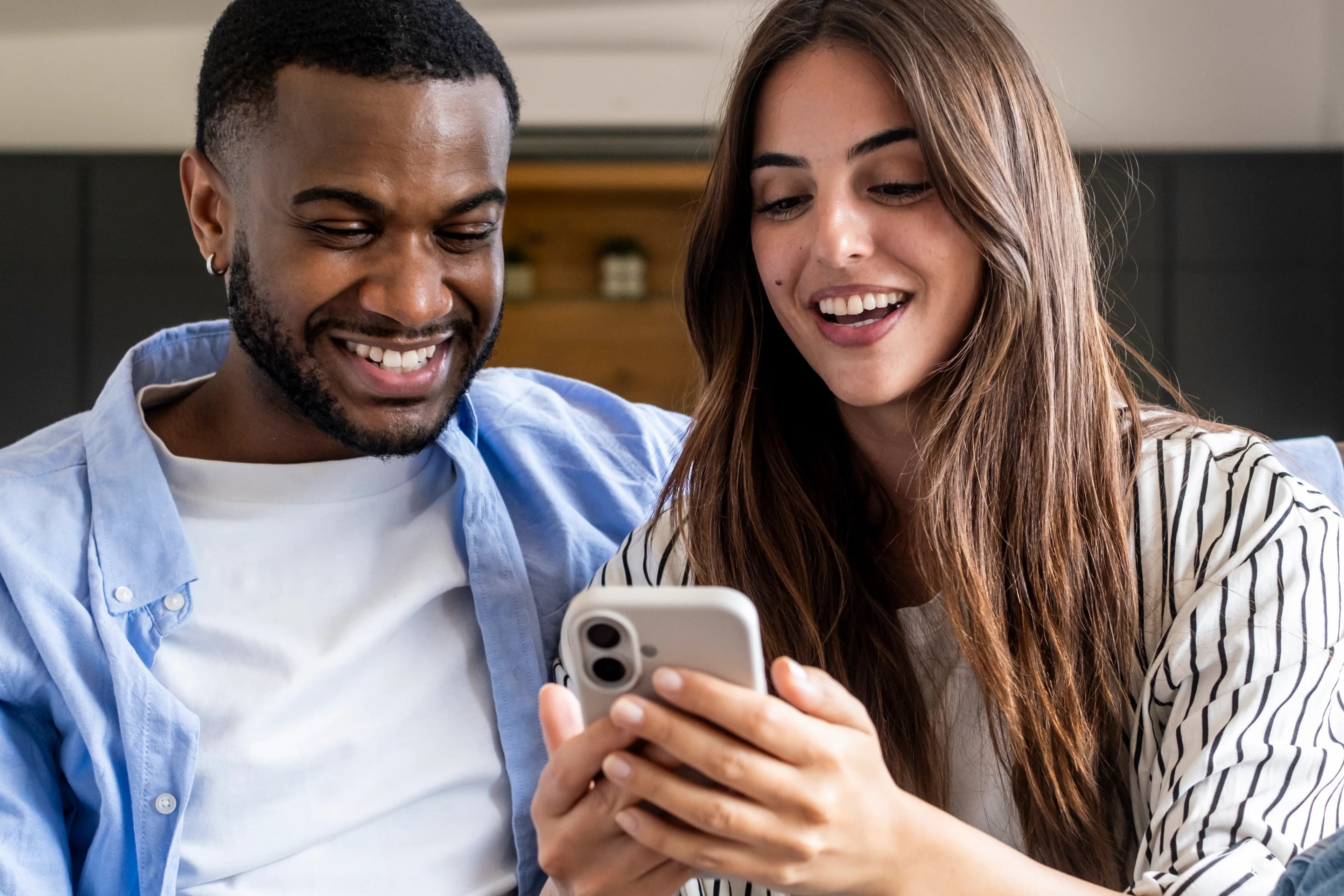 Two people smiling as they look at a smartphone together